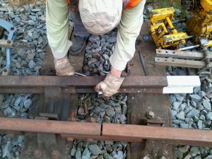 Miles Rhodes bolting in a track circuit interrupter onto a rail
