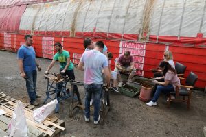 Nationwide Building Society volunteers are seen wire brushing track nuts and bolts, with others using threading taps to clean the threads of some track nuts.