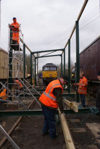 With all of the uprights in place along with two of the roof girders; the infrastructure team prepare to install one of the outer roof beams on 18 Feb 2018. Photo Credit: Tim Casentieri